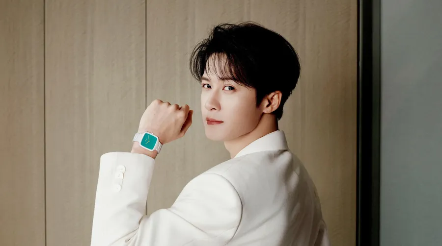 Tan Jianci in a white suit raises his wrist to show the Rado True Square Thinline with turquoise dial